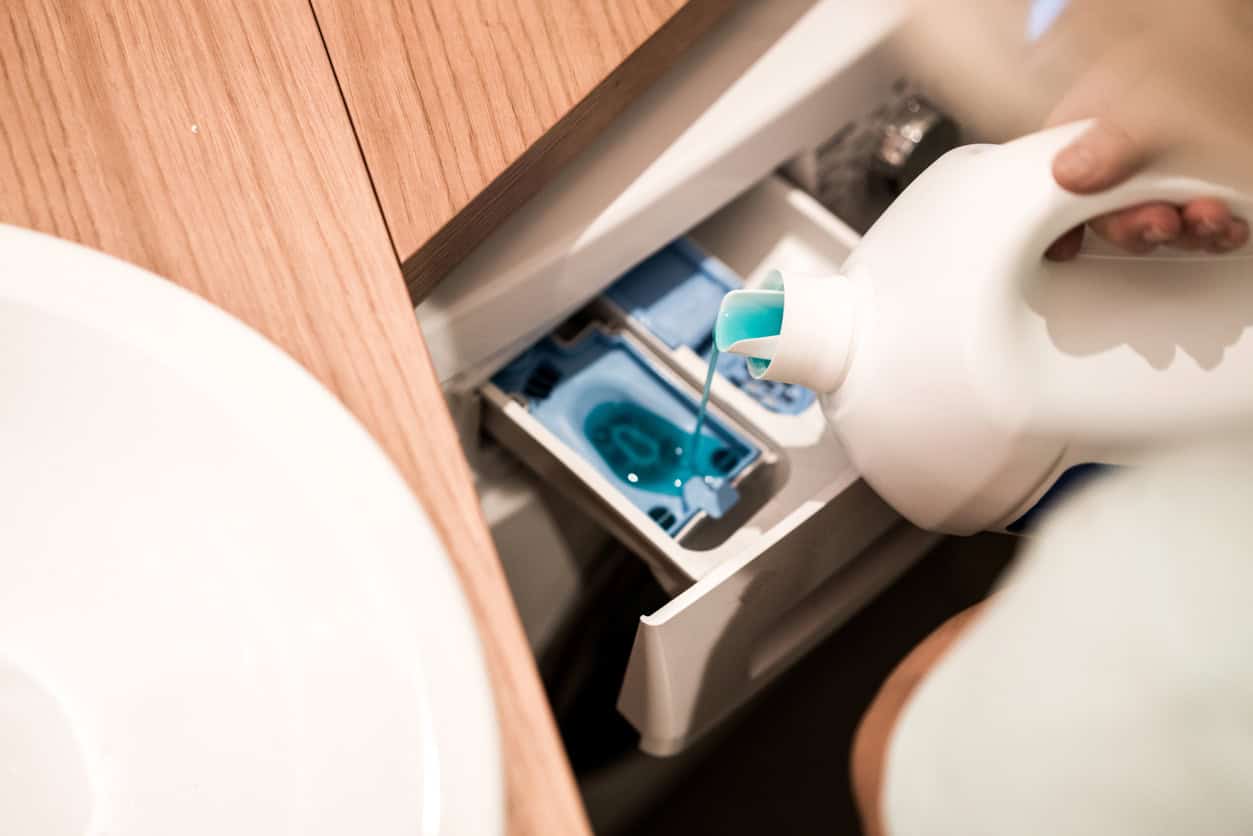 A person putting laundry detergent into the washing machine