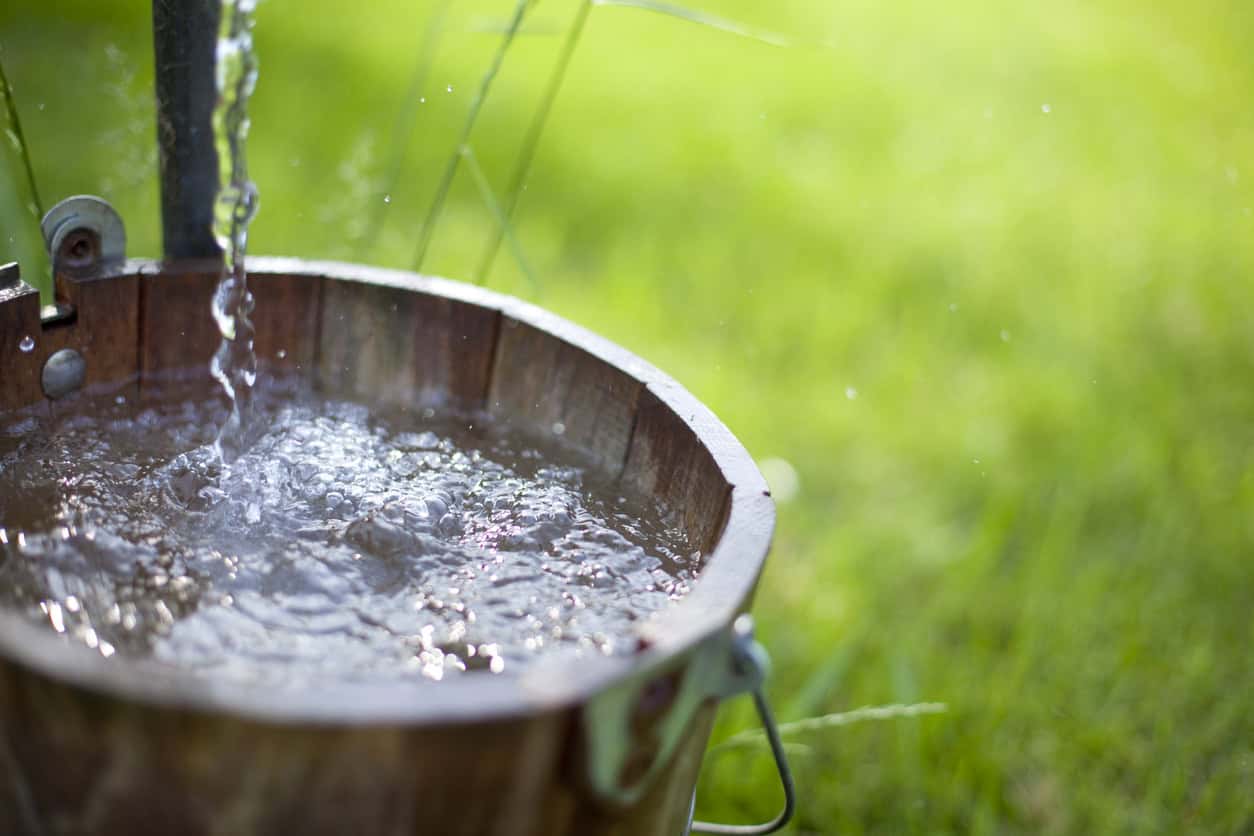 A wooden bucket getting filled with well water