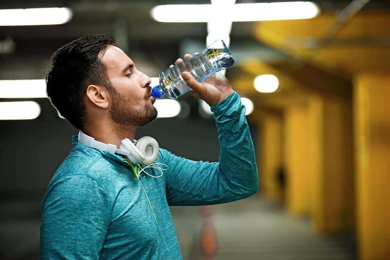 Man is drinking water and relaxing after jogging.