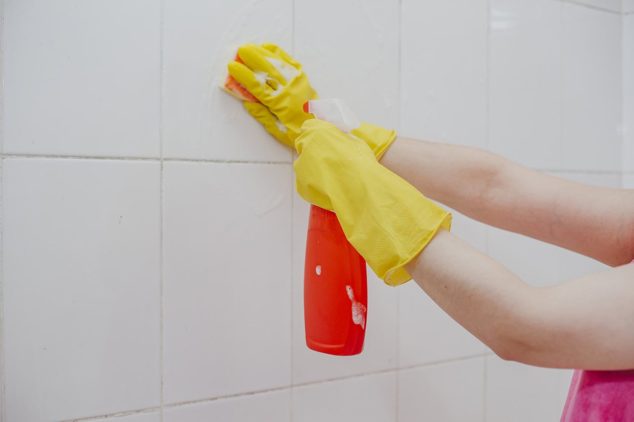 Cleaning bathroom tiles. Women washing bath walls. Housemaid cleaning up tiles of bath. House holding jobs.