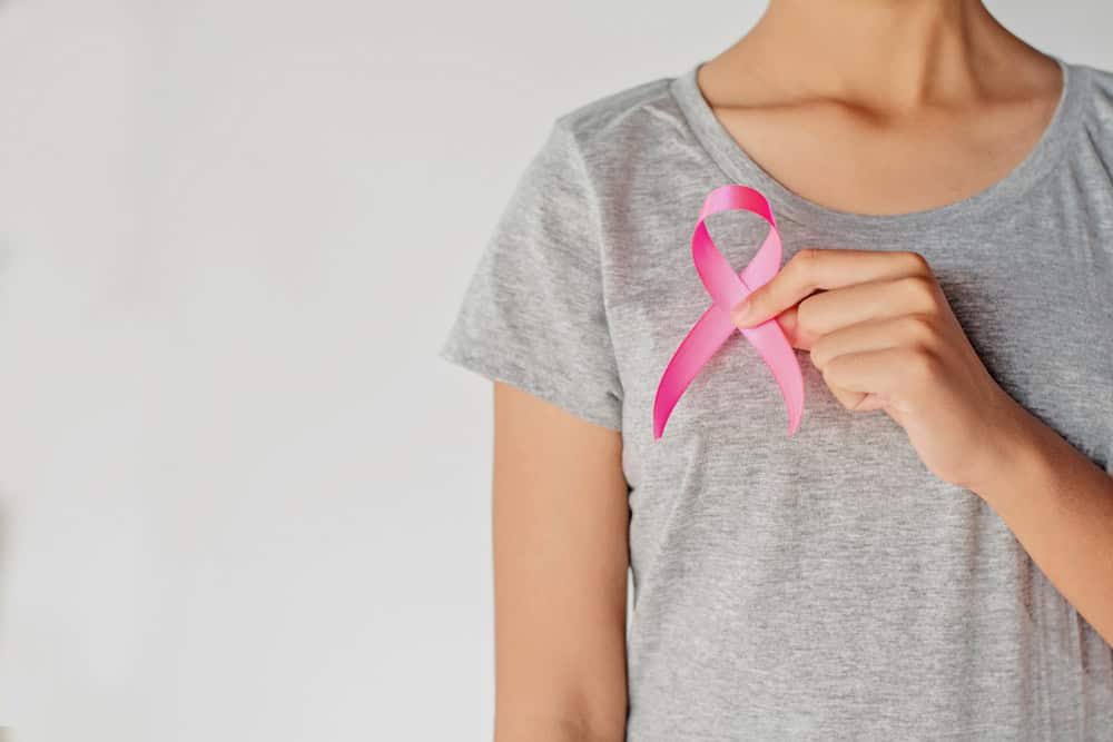 A lady holding a breast cancer awareness ribbon