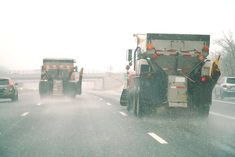 truck on highway during snow storm in winter delivering road salt