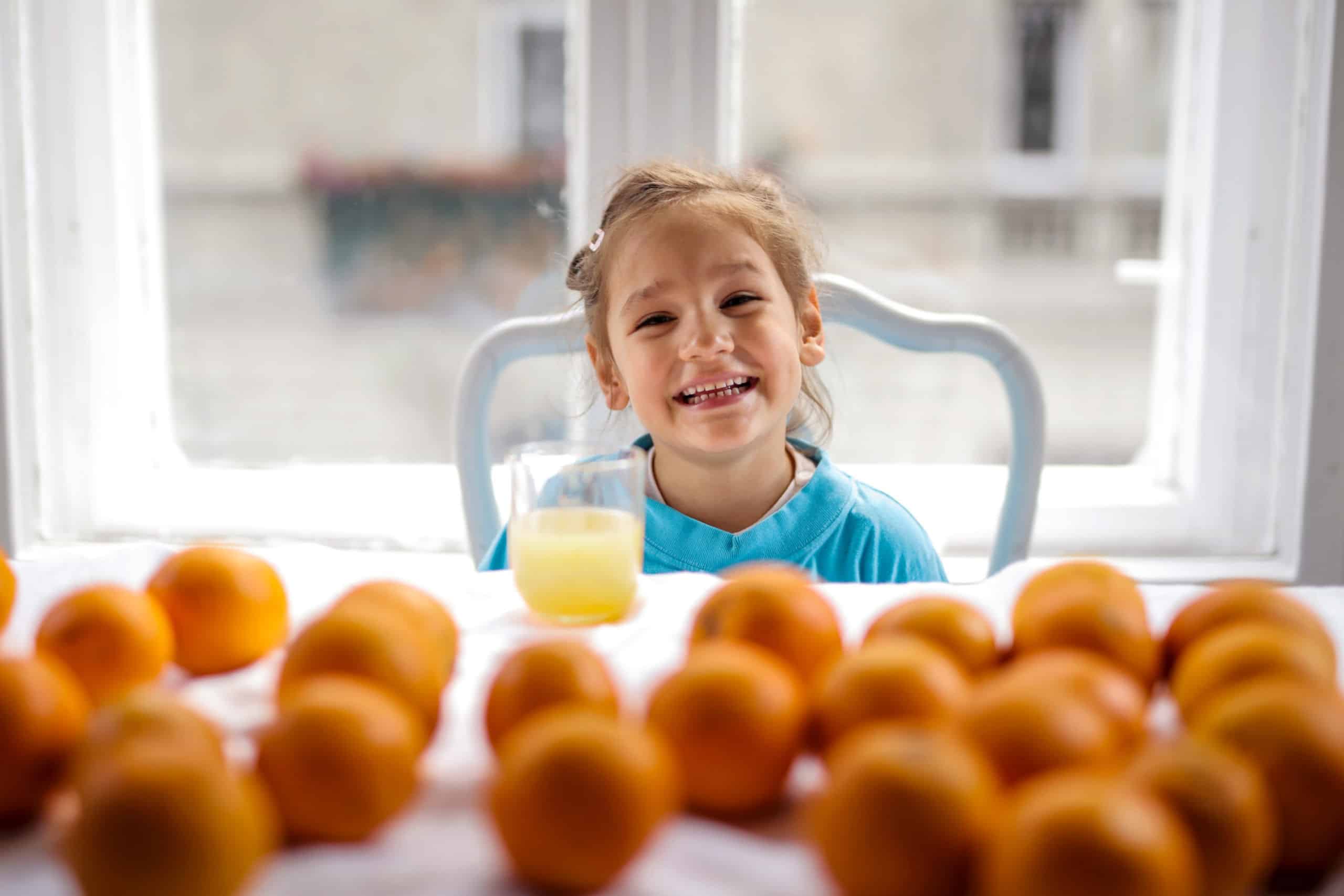 Girl smiling with orange juice in glass on table