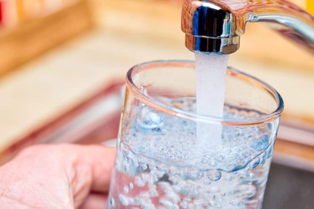 man-pouring-a-glass-of-water-from-kitchen-faucet-in-stillwater-mn