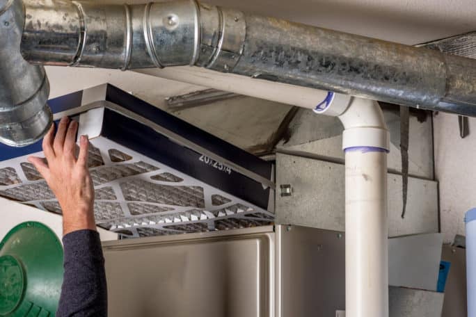 Handyman replaces a furnace filter with a clean one after repairs