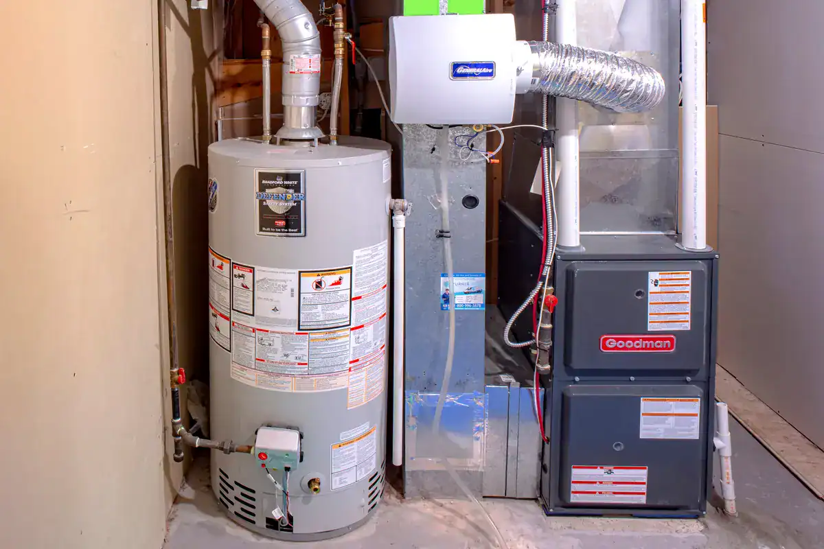 A basement utility area with a light gray water heater on the left and a dark gray