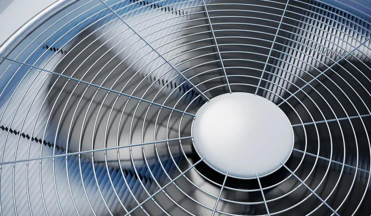 Close-up of a spinning metal fan with a protective grid covering the blades, reflecting light. The image captures the dynamic motion and circular pattern of this Bemidji HVAC system as it operates, offering a glimpse into its efficiency and design.