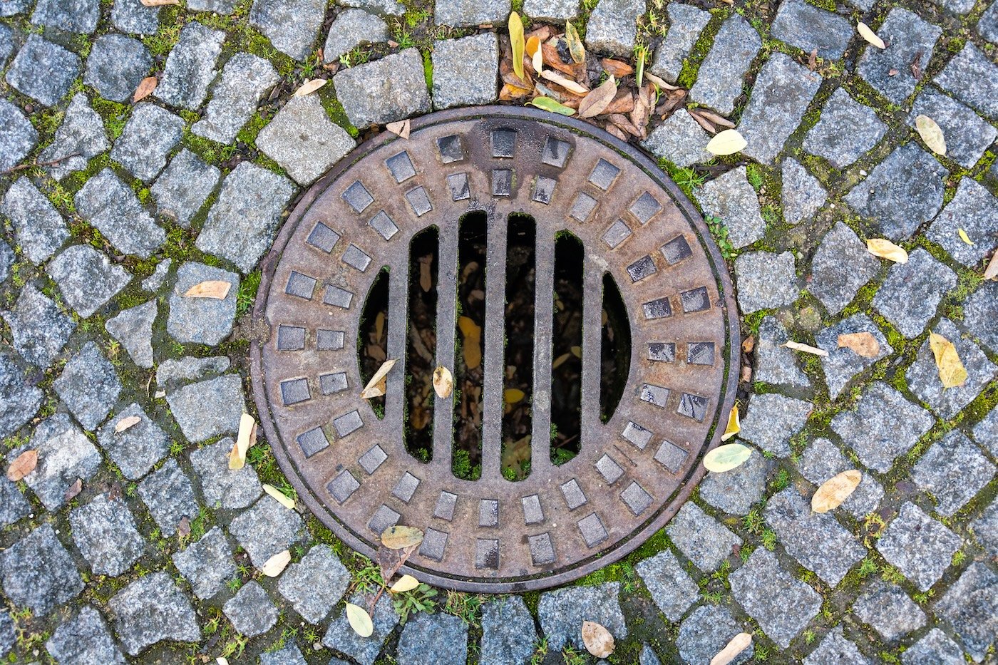 Rusty Sewer Manhole In Paving Stones, Close Up