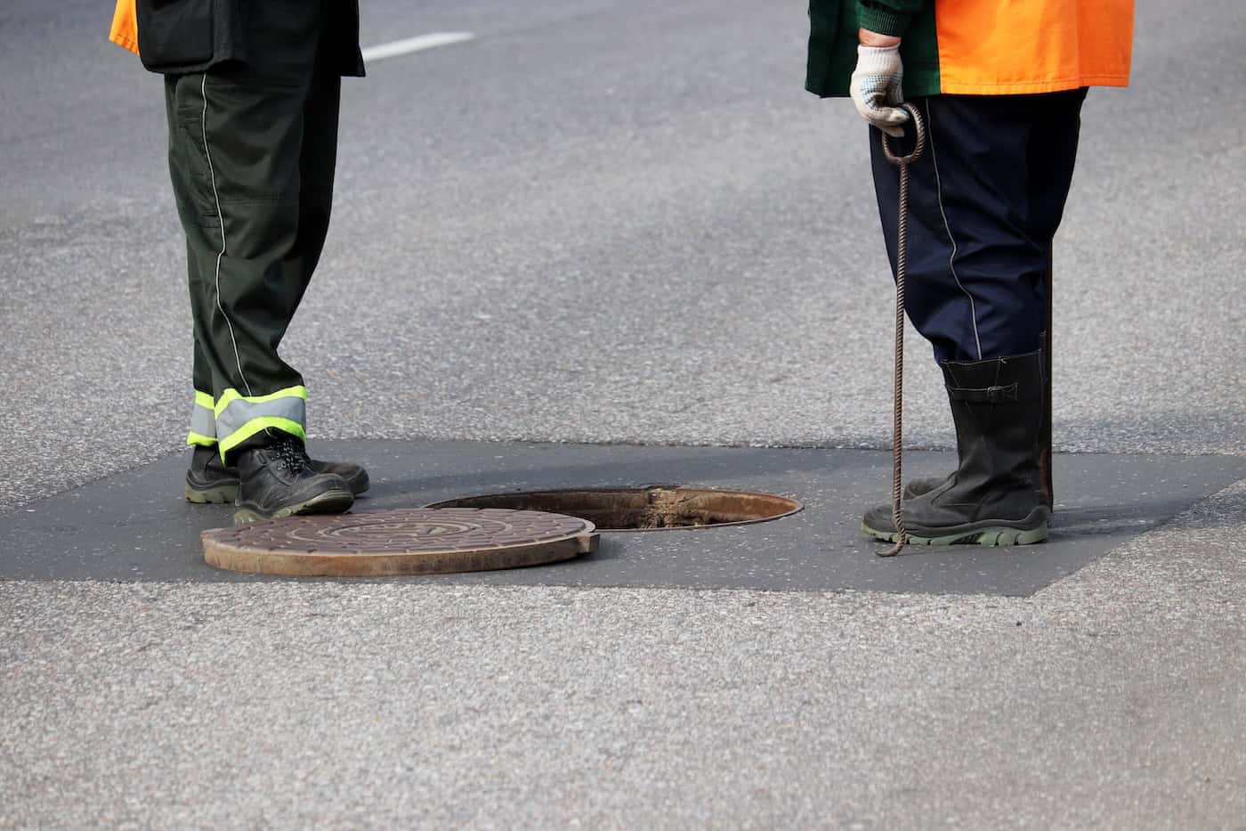 Workers Over The Open Sewer Hatch On A Street. Concept Of Repair Of Sewage, Underground Utilities, Water Supply System, Cable Laying, Water Pipe Accident