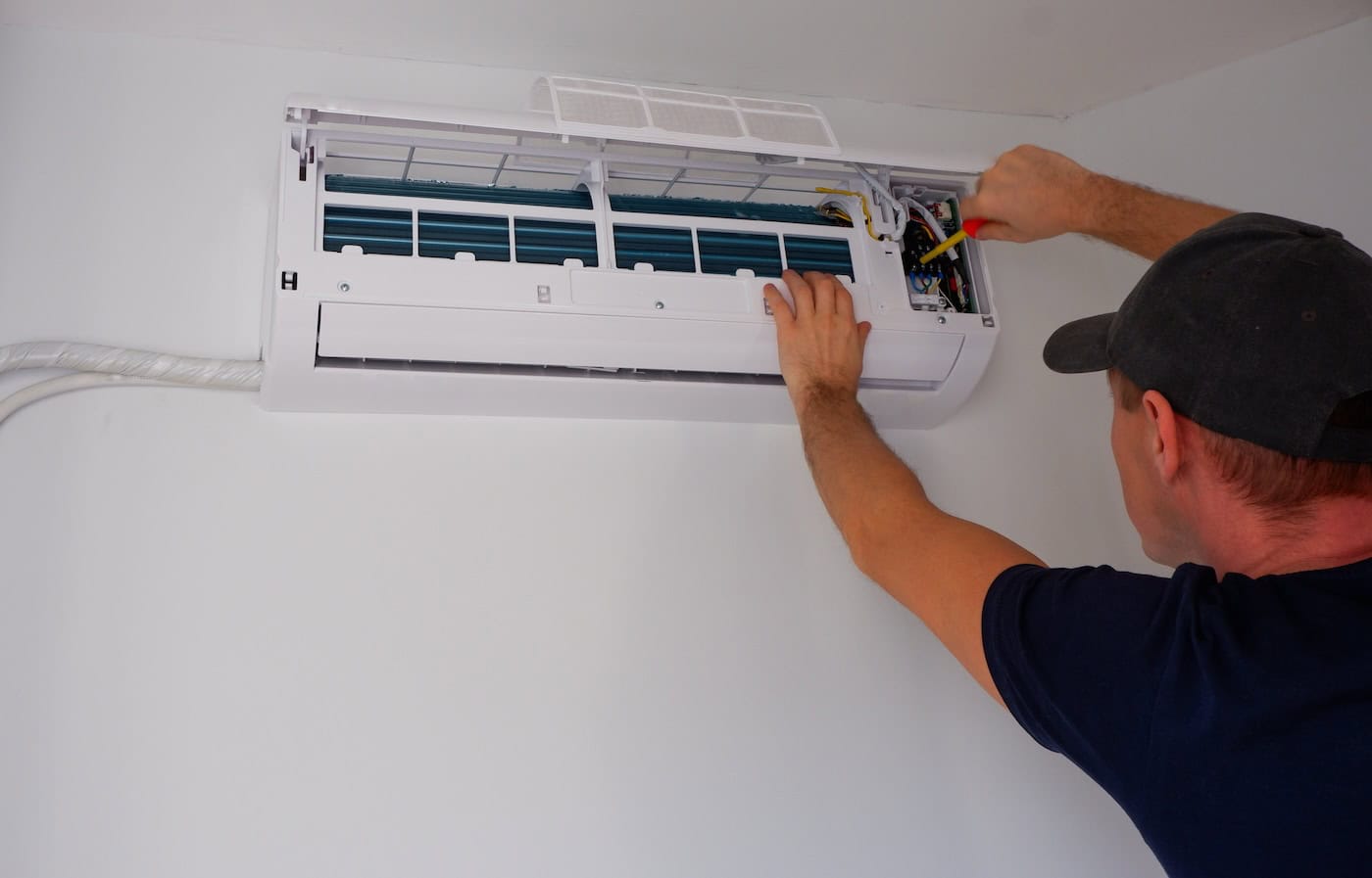 Maintenance Of The Air Conditioner. The Service Engineer Unscrews The Contacts With A Screwdriver. View Of The Hands.