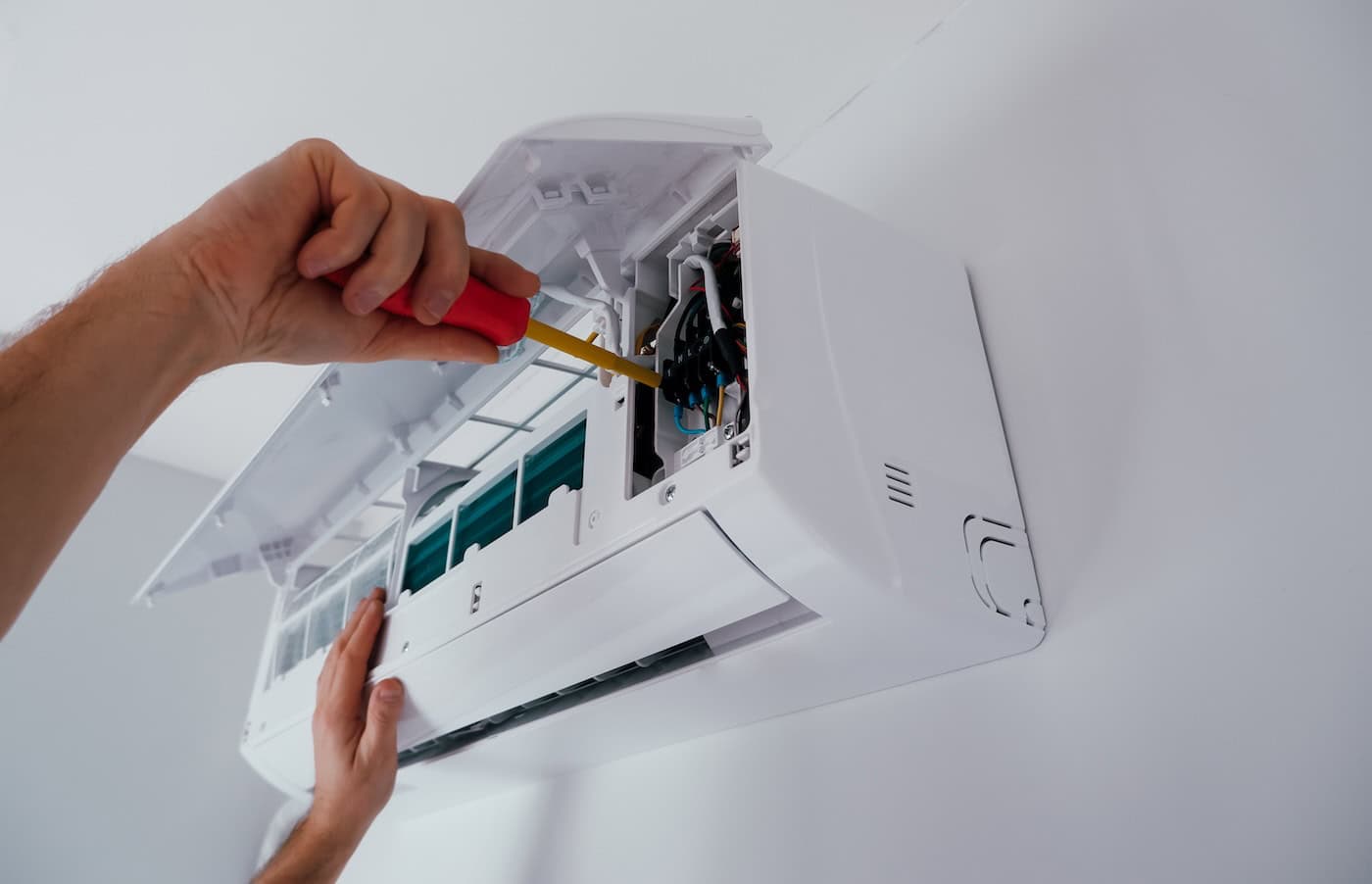 Repair And Maintenance Of The Air Conditioner. A Technician Repairs An Air Conditioner. Close Up View Of The Hands Of A Working With A Screwdriver.