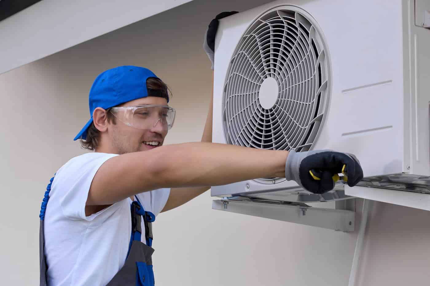 Man Air Conditioner Repair Technician With Tool Tightening Bolts On Metal Mount